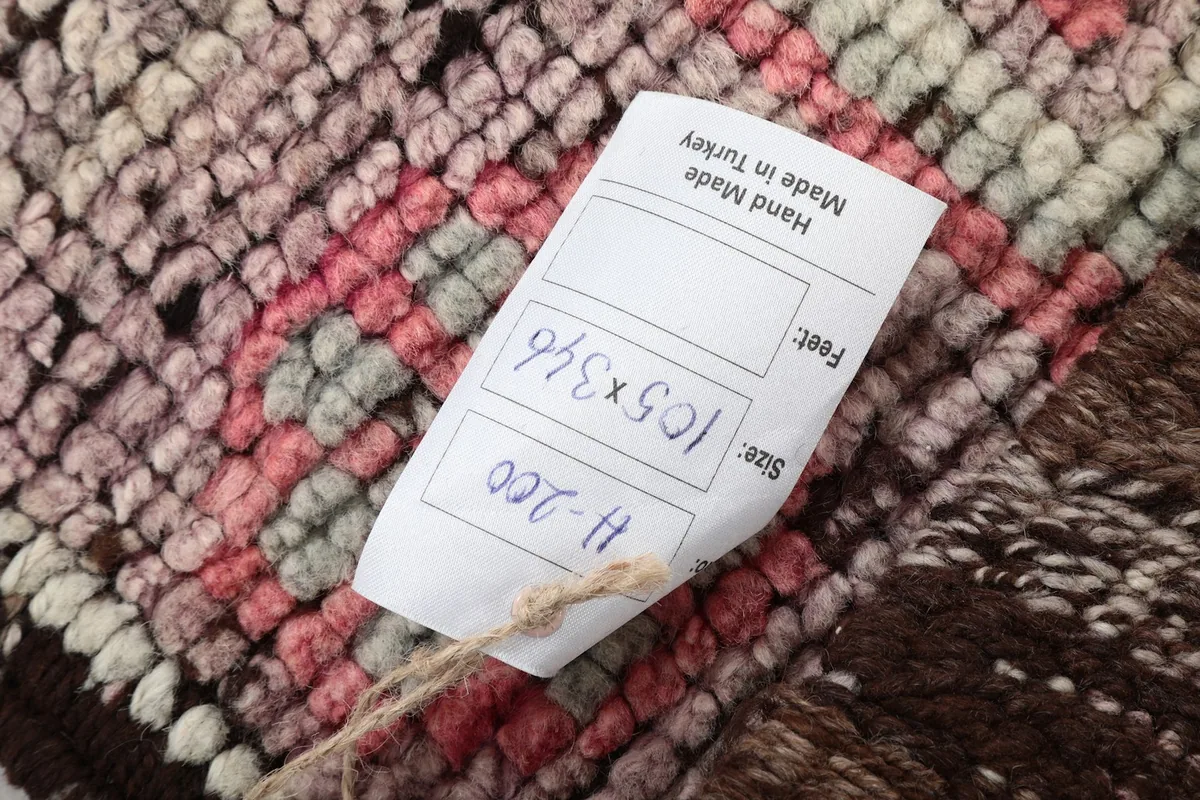 Detail of the product tag attached to the rug, displaying its size in centimeters and feet
