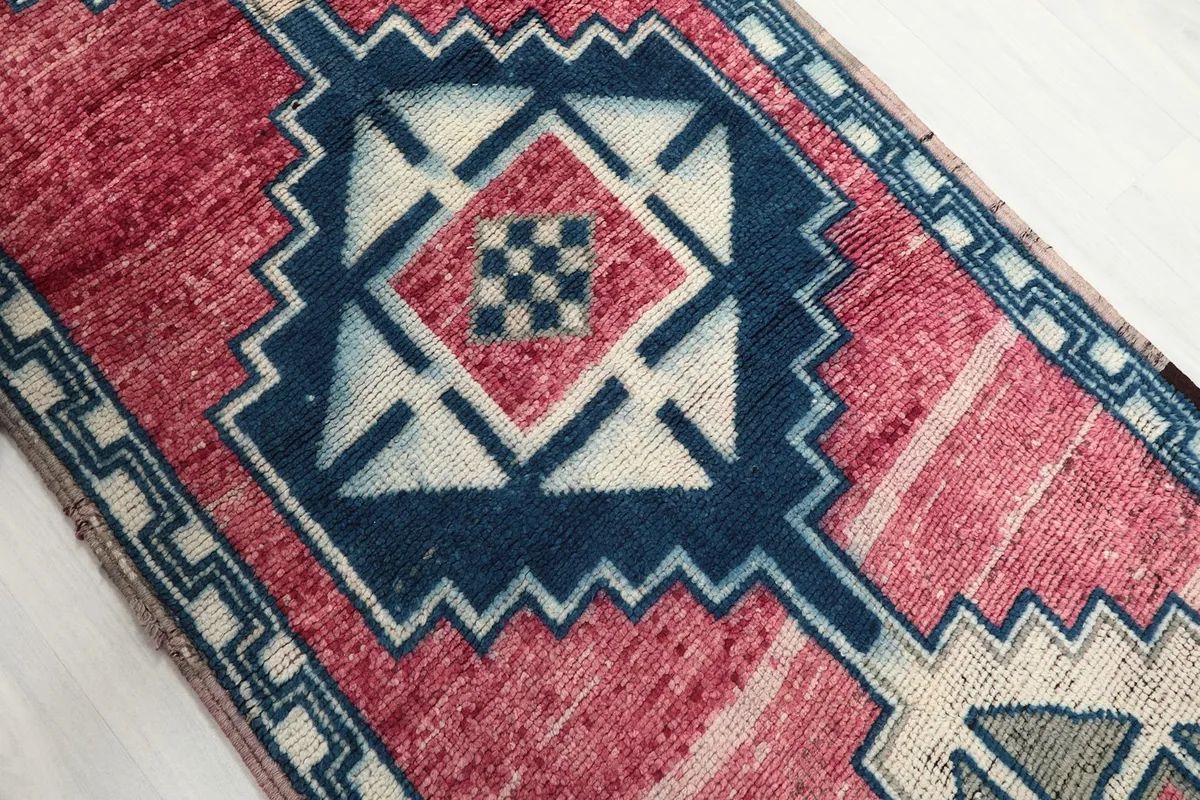 Close-up of the central navy and ivory geometric motif on the rose background.
