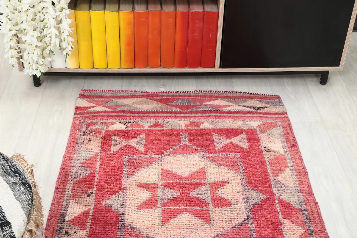 Angled view of one end of the red runner rug with a bookshelf in the background