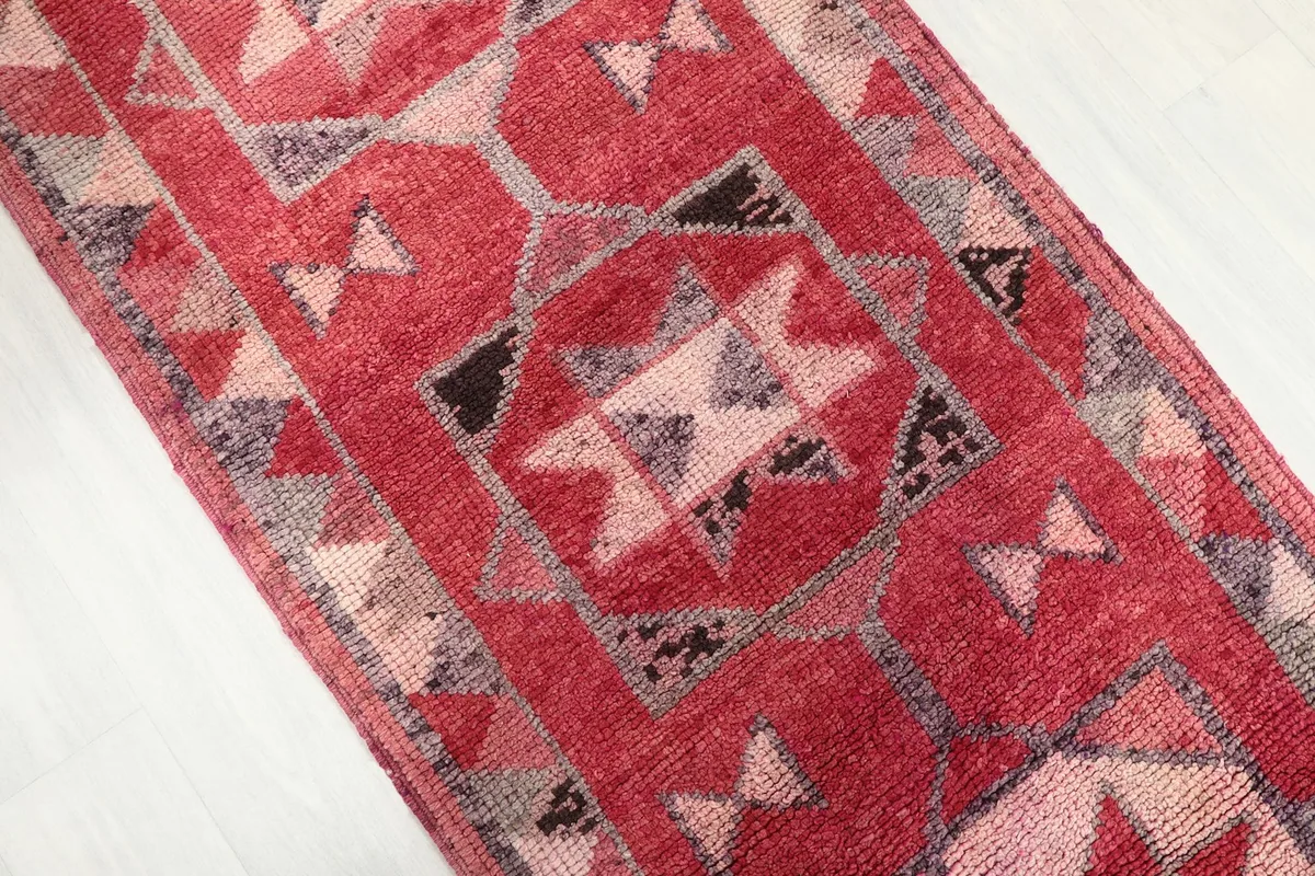 Detail view of a central geometric motif in red, pink, and gray tones