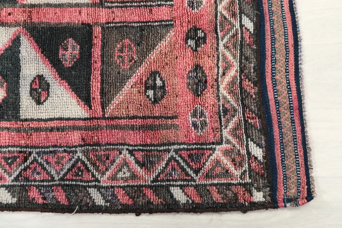 Detailed view of the corner and border patterns featuring triangles and small symbols in rose, black, and ivory.
