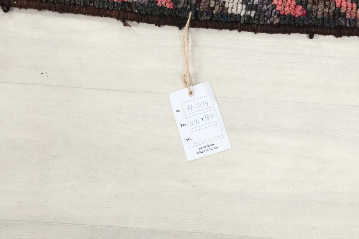Product tag displaying the rug's dimensions and hand-knotted origin on a white floor.