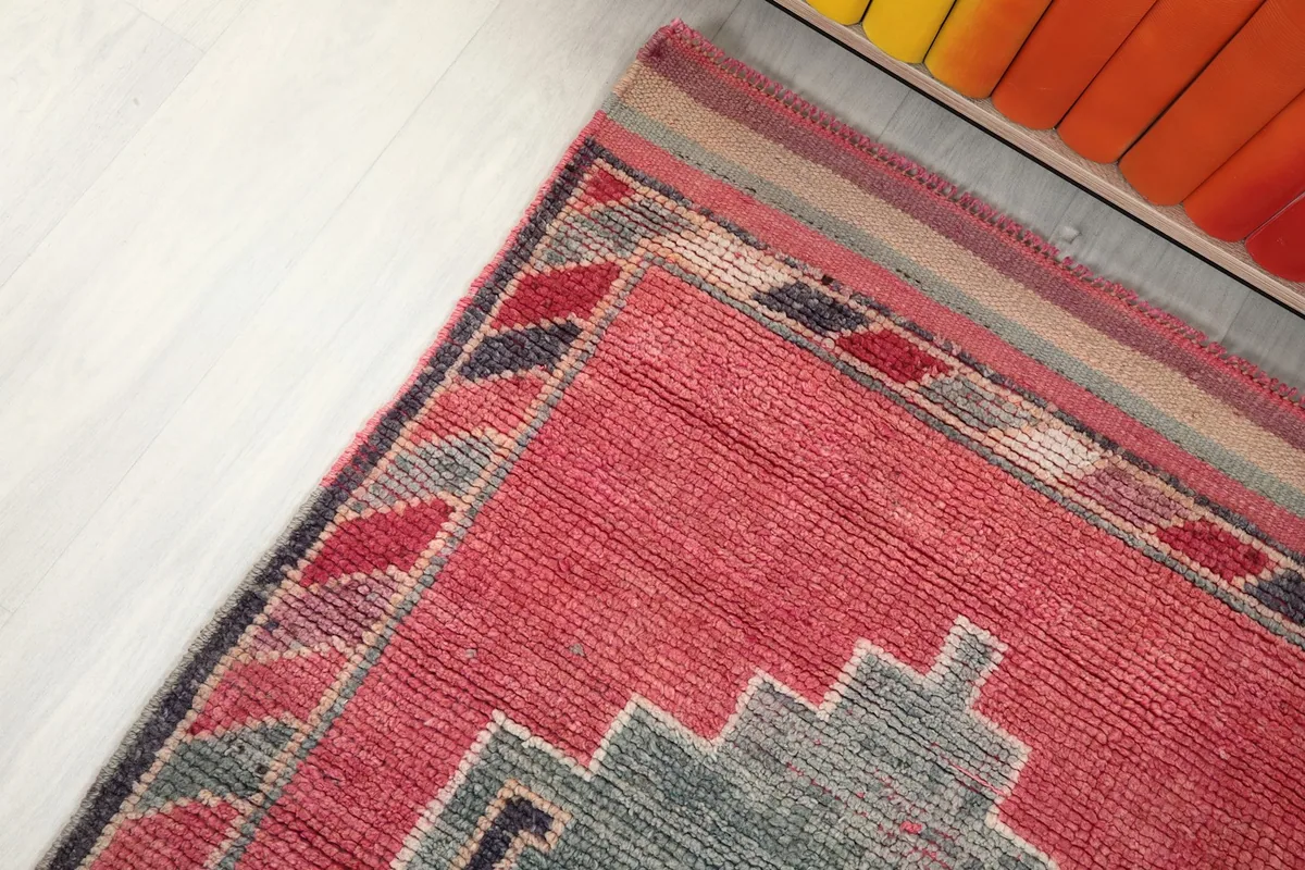 Corner detail of the rug's border with striped patterns in various colors, and the main rose field