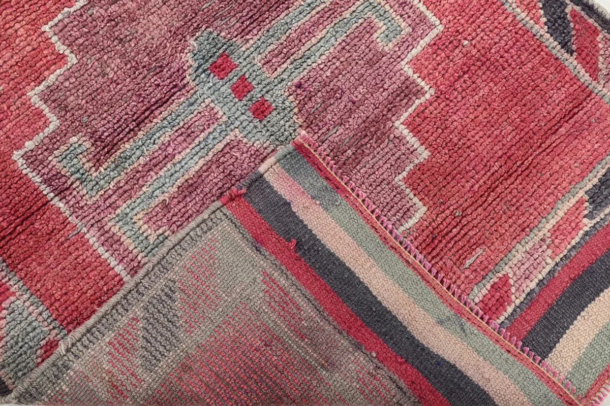 Folded corner of the rug revealing the cotton foundation and the reverse side of the hand-knotting