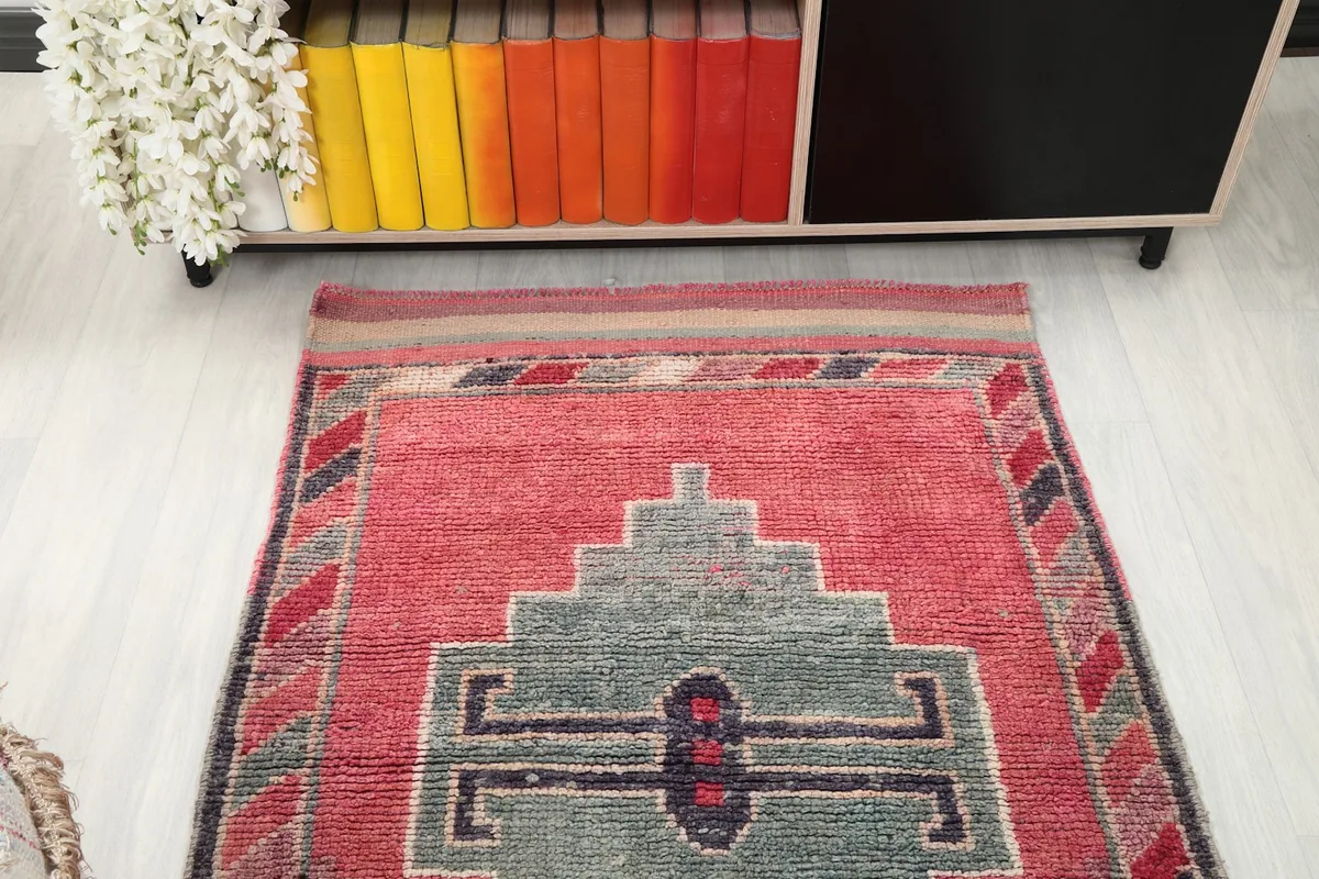 Overhead view of one end of the rose runner rug, showing the border and a gray geometric motif