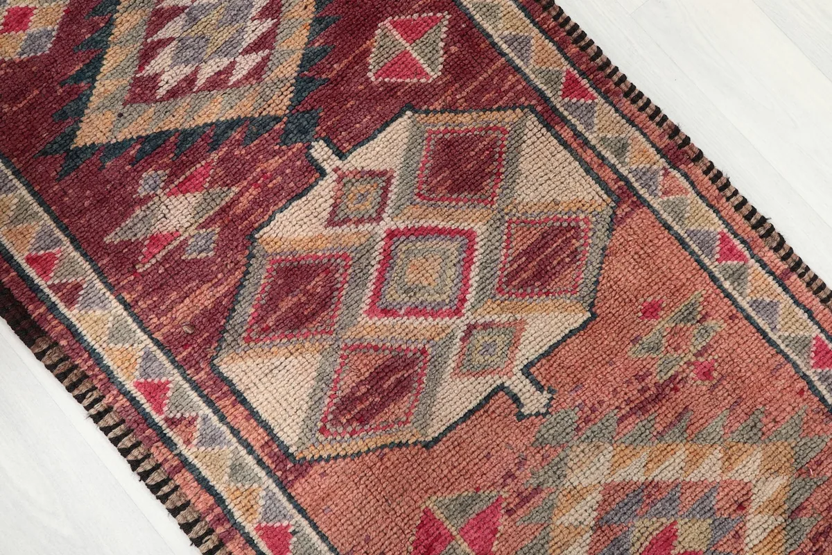 Angled close-up showing the varied geometric motifs and colors of the rug