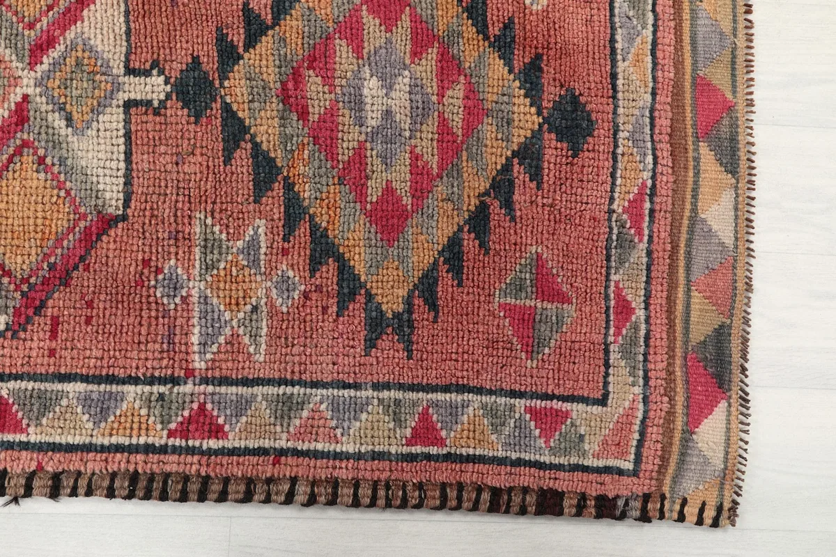 Detailed view of the geometric patterns and border on the rust and red runner