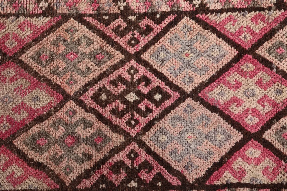 Intricate detail of the tribal motifs within the geometric design, showing varied colors and knotting.