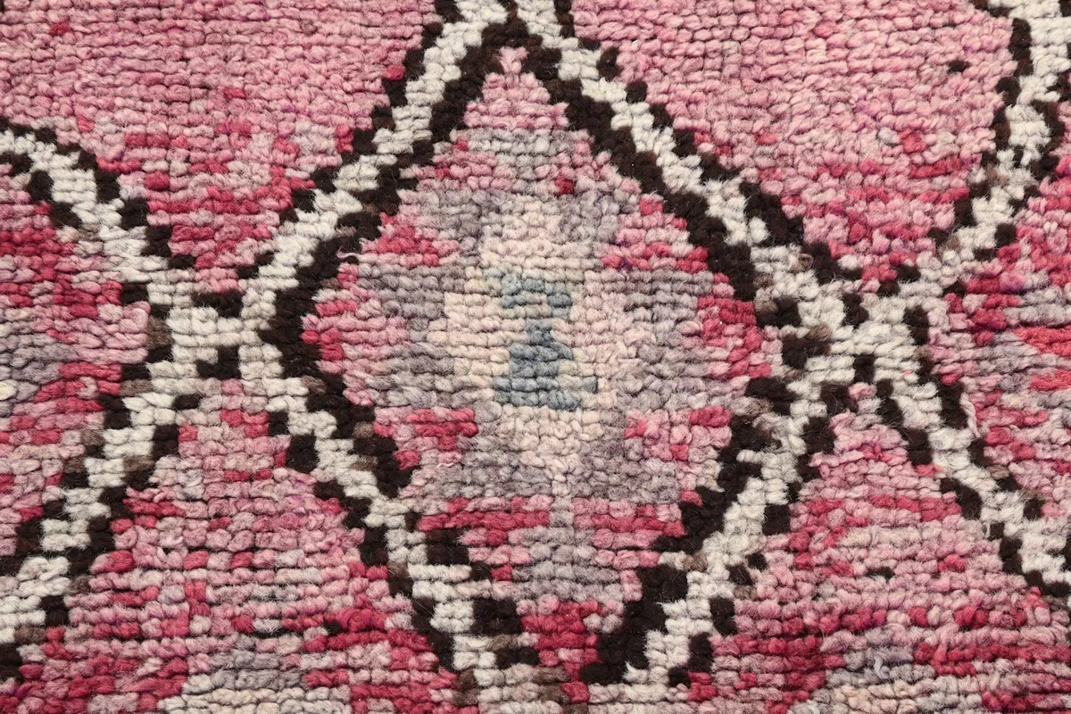 Extreme close-up of the low wool pile, revealing the texture and varied rose, gray, and black threads