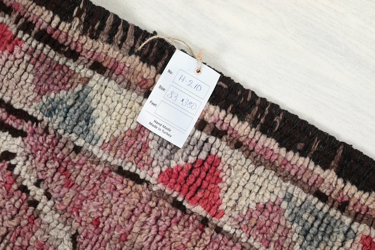 Detail of the rug's texture and colors with a product tag visible, showing its vintage quality