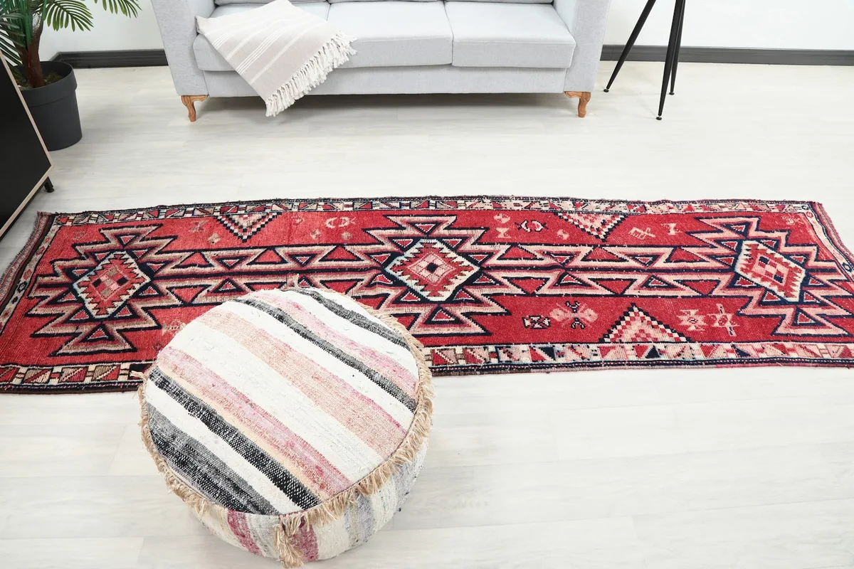 Full length view of the runner rug in a room, with a decorative pouf in the foreground.