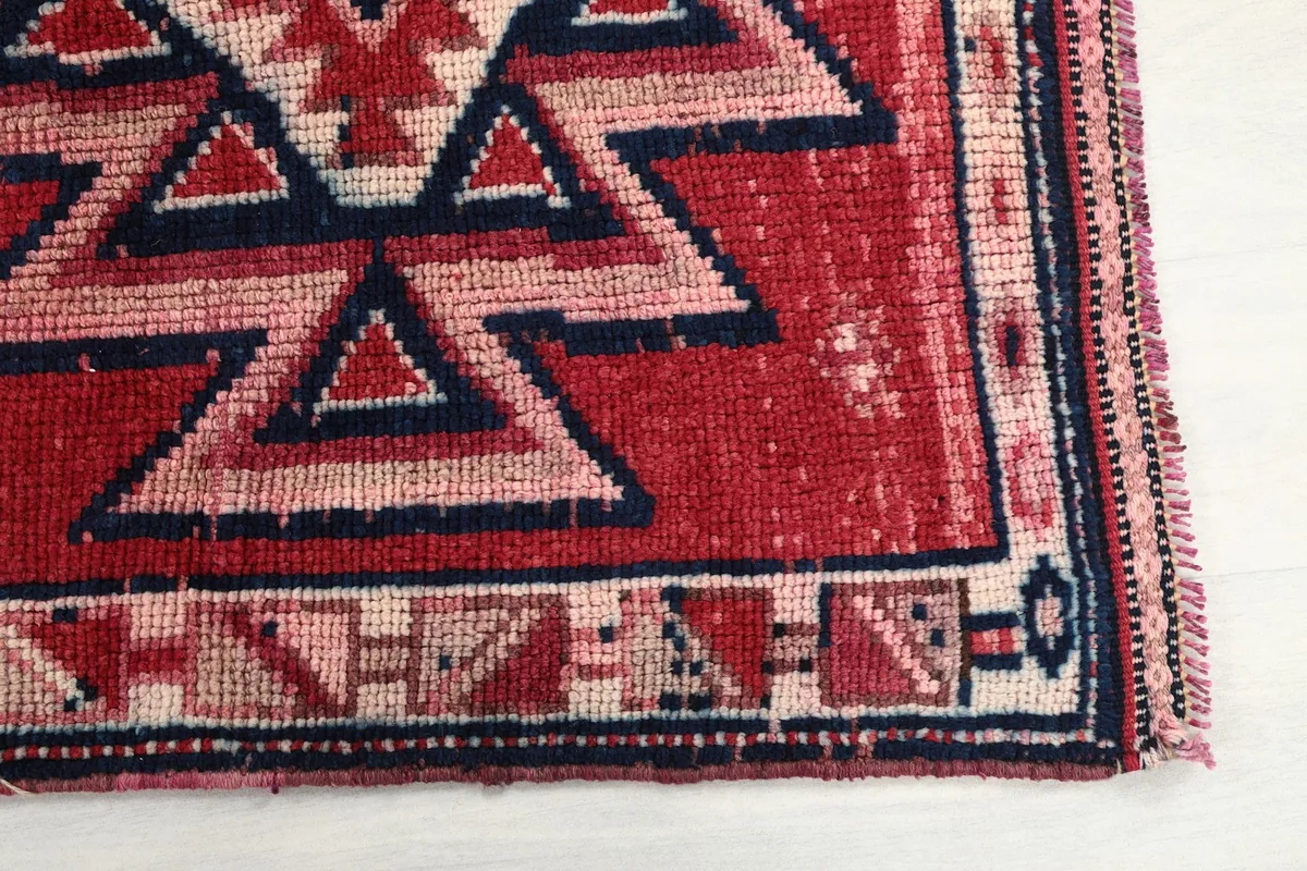Detailed view of one end of the rug, showing the geometric border and slight wear along the edge.