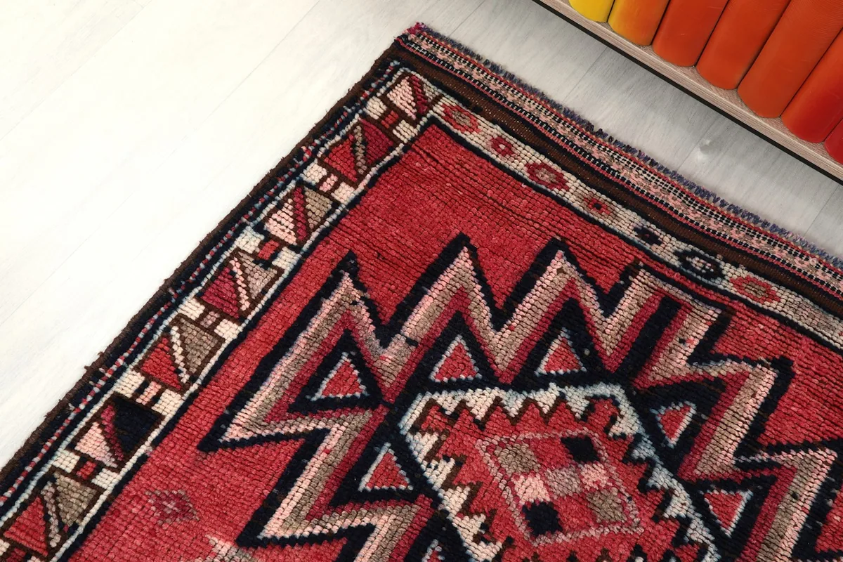 Corner detail of the rug, illustrating the geometric border design and the transition to the main field.