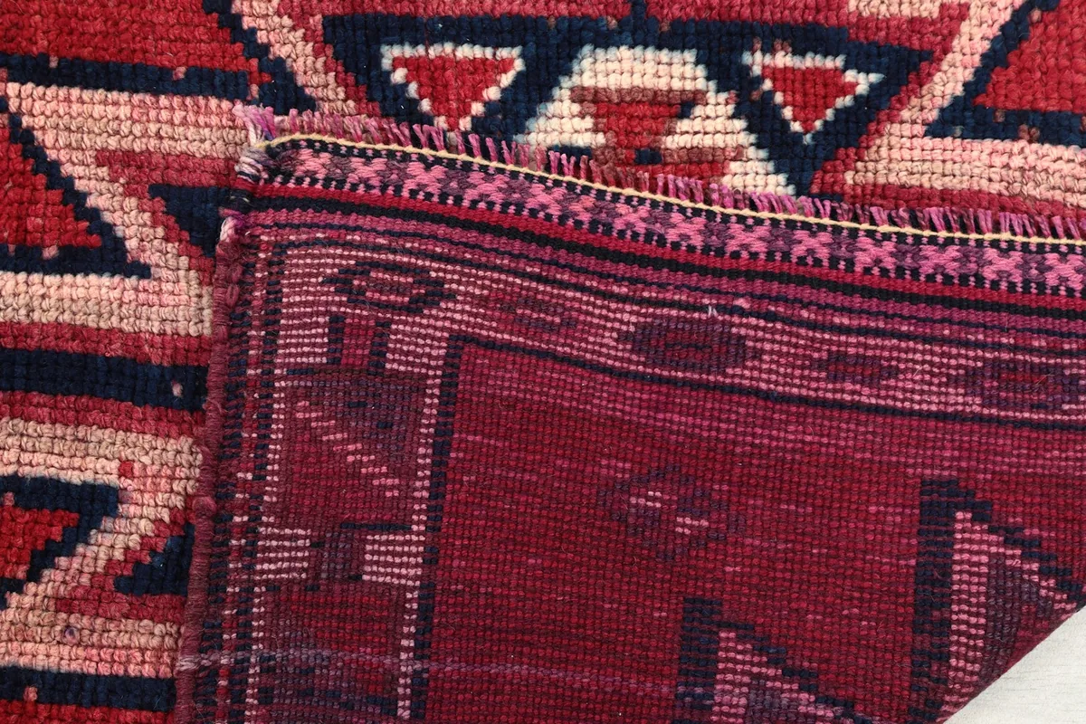 Close-up of the folded rug, showing the cotton foundation and the reverse side of the hand-knotted pile.
