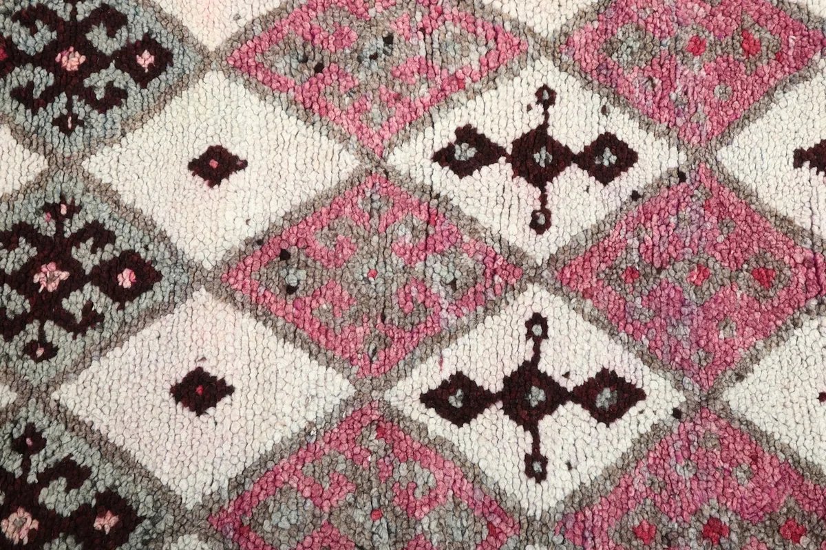 Close-up of the hand-knotted wool pile and the distinct pink, ivory, and brown patterns.