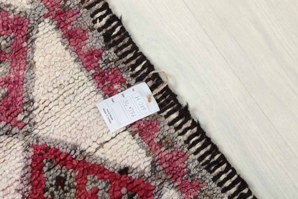 Close-up of the rug's pile and fringe with a product tag attached, indicating authenticity.