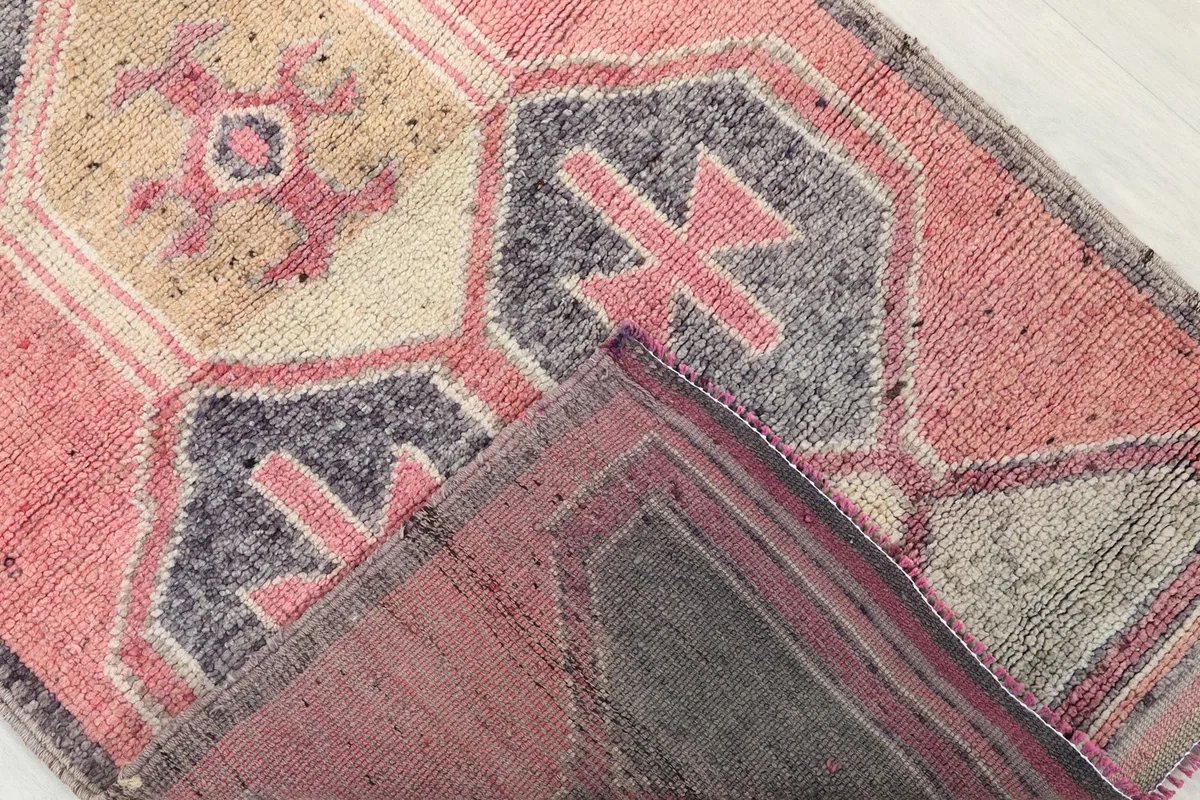 View of the runner rug folded back, showing the back of the rug and the foundation