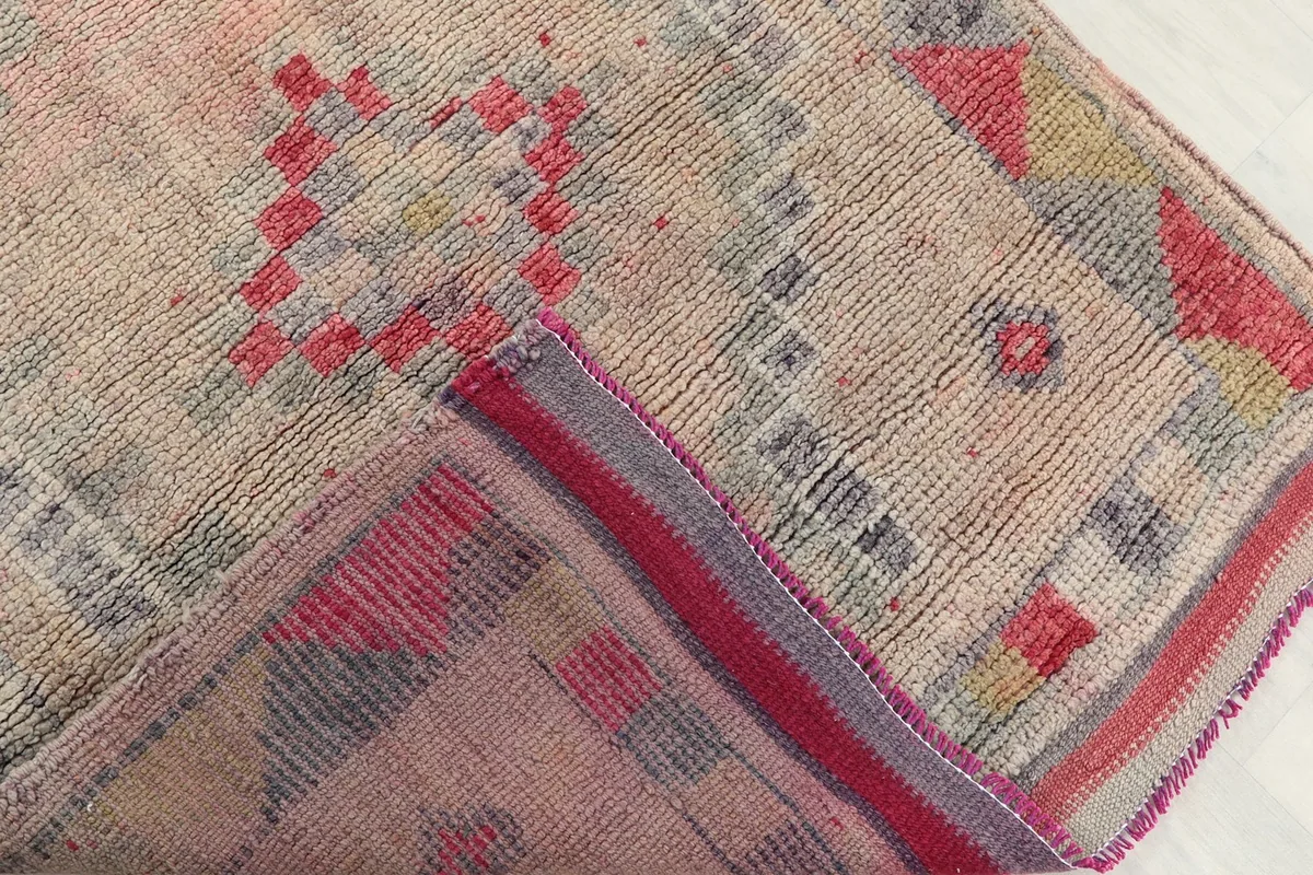 Corner of the rug folded to show the wool pile and the hand-knotted cotton foundation.