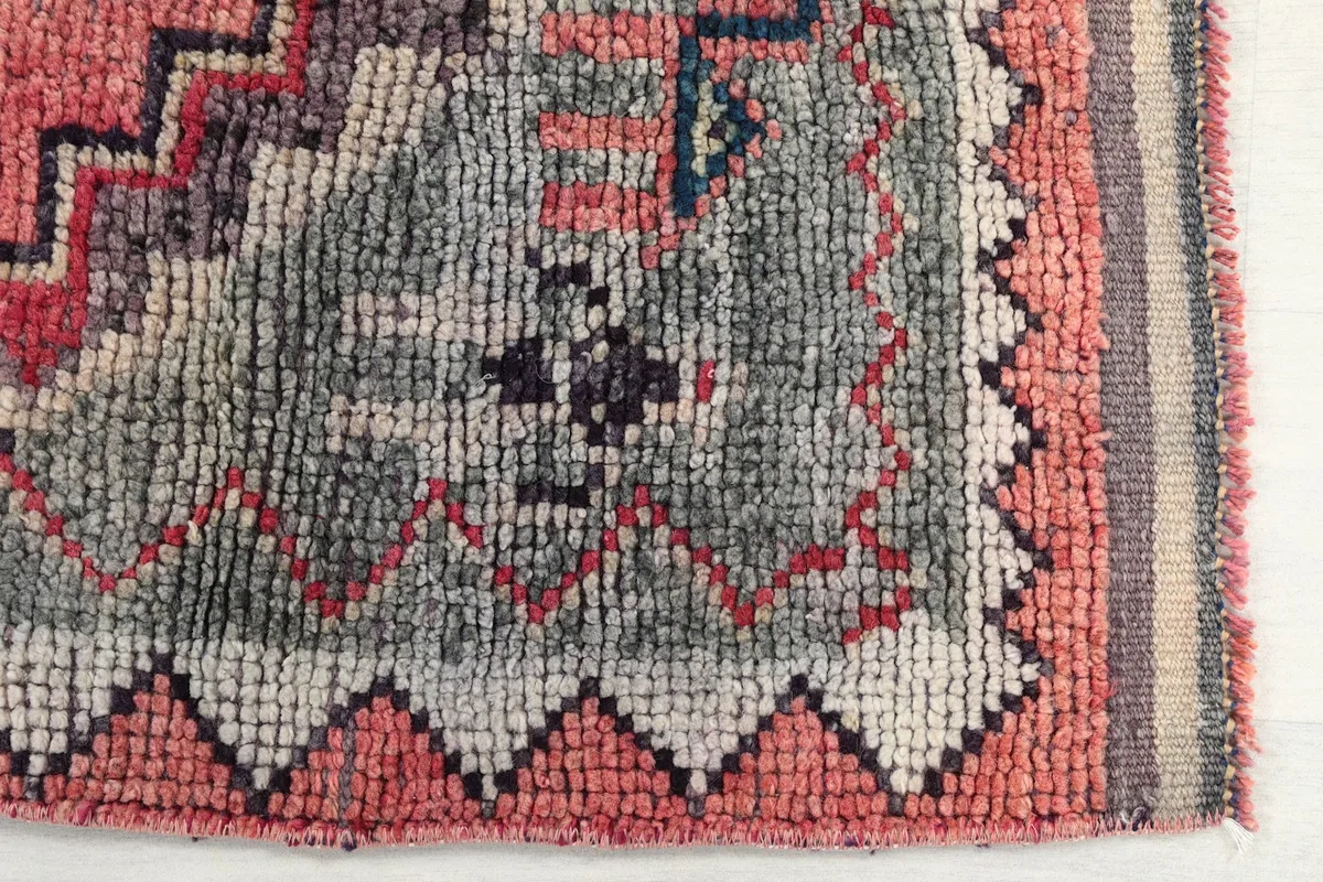 Detailed view of the rug's gray and rose sections with intricate geometric weaving