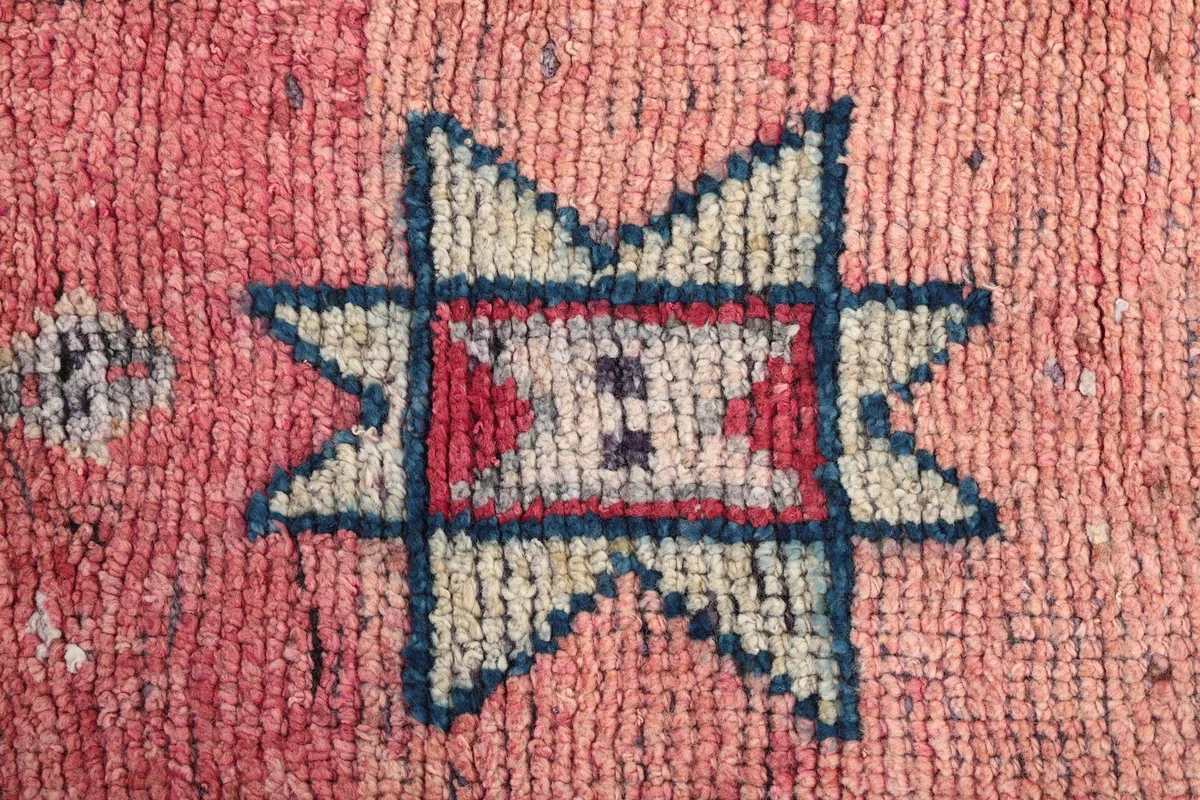 Close-up of a prominent cream and navy star-like geometric motif on the rose field