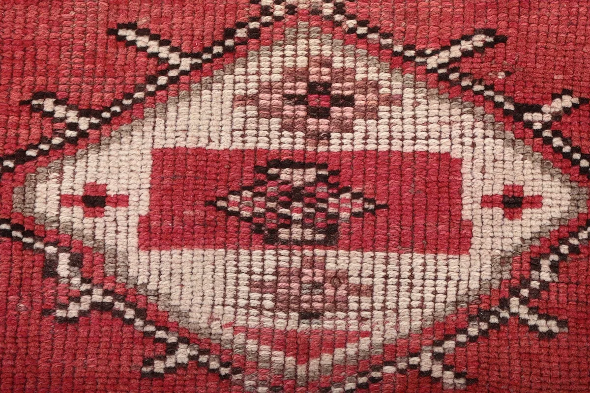 Extreme close-up showing the hand-knotted wool pile texture and color variations of a central motif