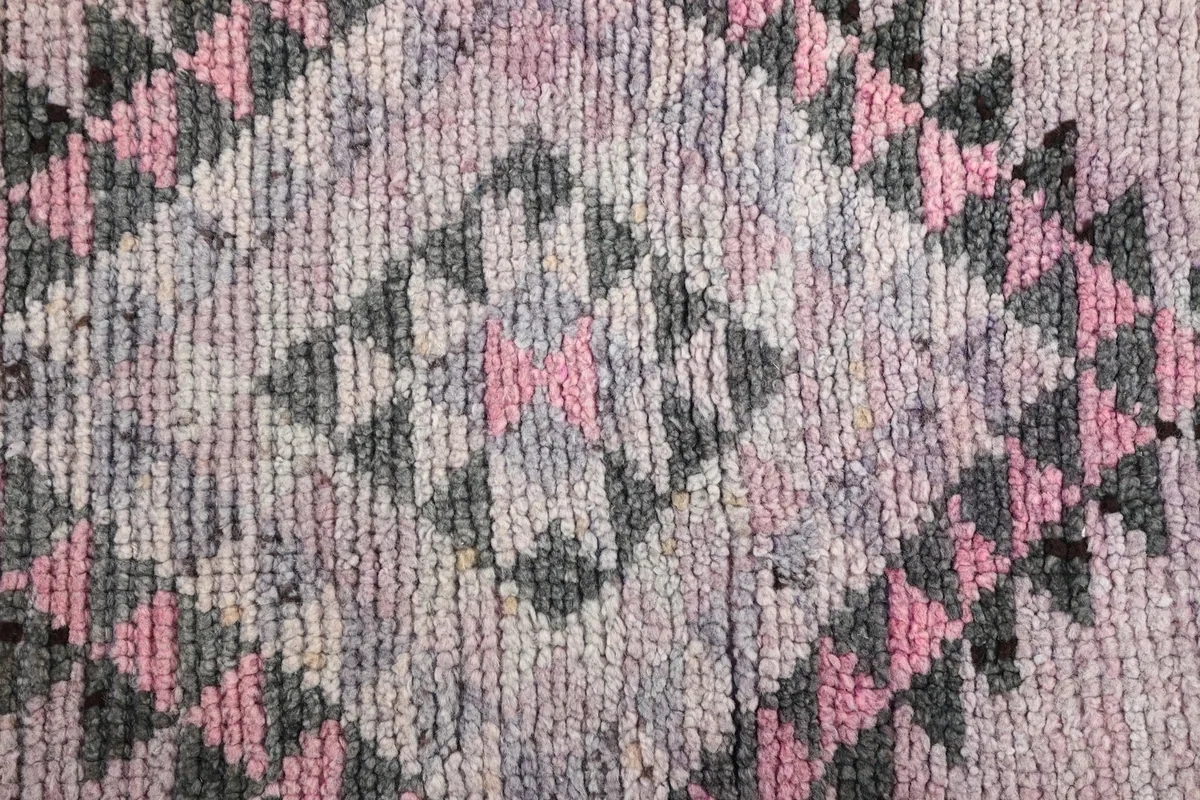 Macro view of the hand-knotted wool pile texture and color blend within a geometric design