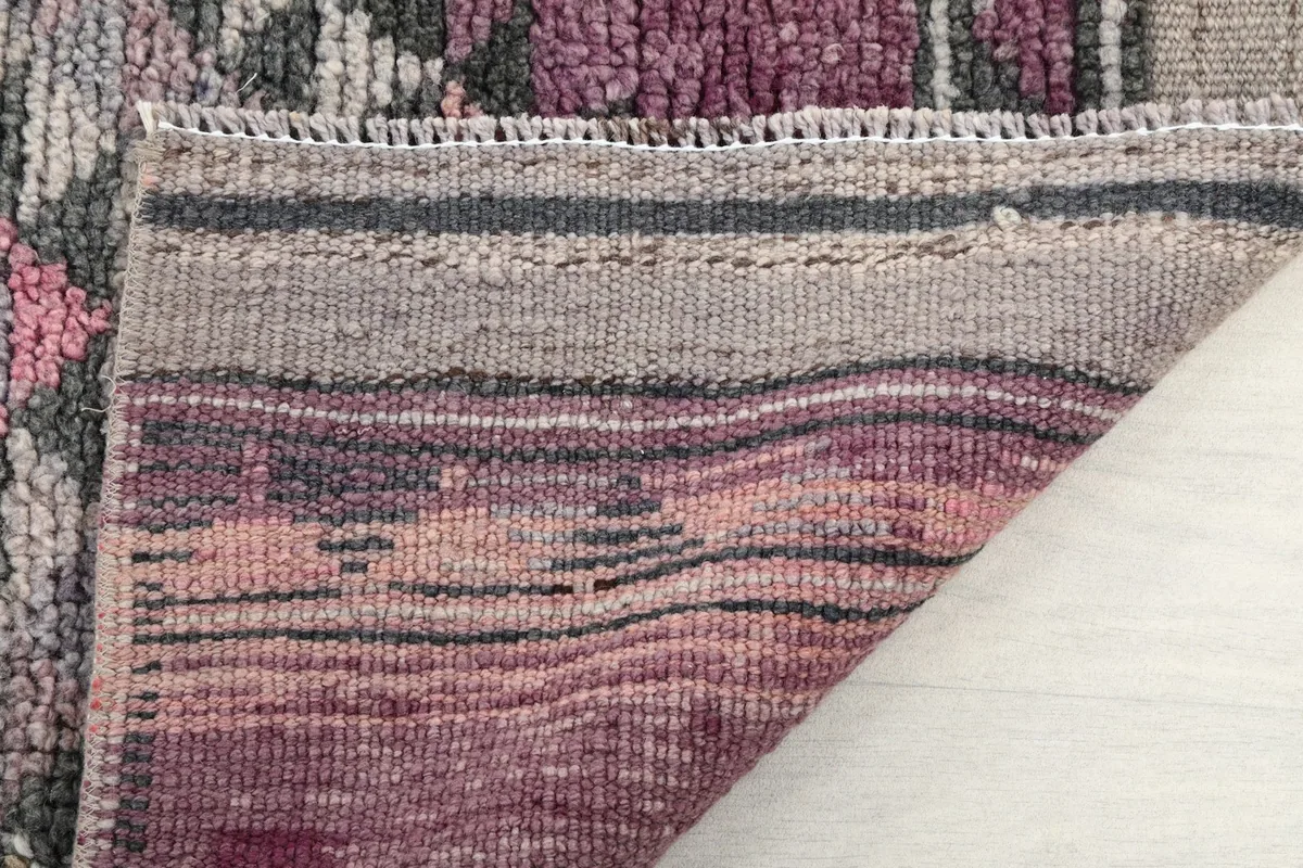 Detail of the rug's edge, foundation, and woven fringe in muted gray and brown tones