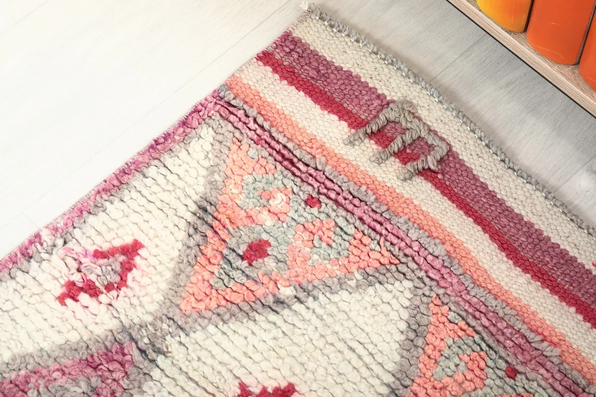Corner detail of the rug, showing border elements and a blend of rose, gray, and ivory
