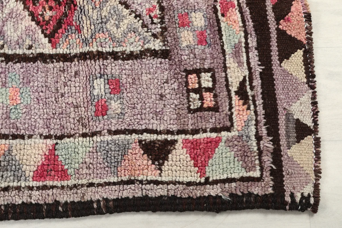 Detail of the runner's edge and geometric border, with purple, rose, and black tones.