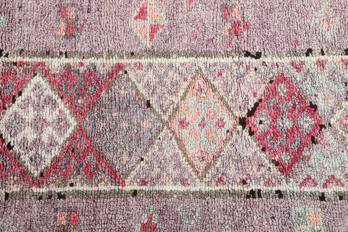 Close-up of the runner's wool pile and hand-knotted texture, showing varied purple and rose diamond shapes.