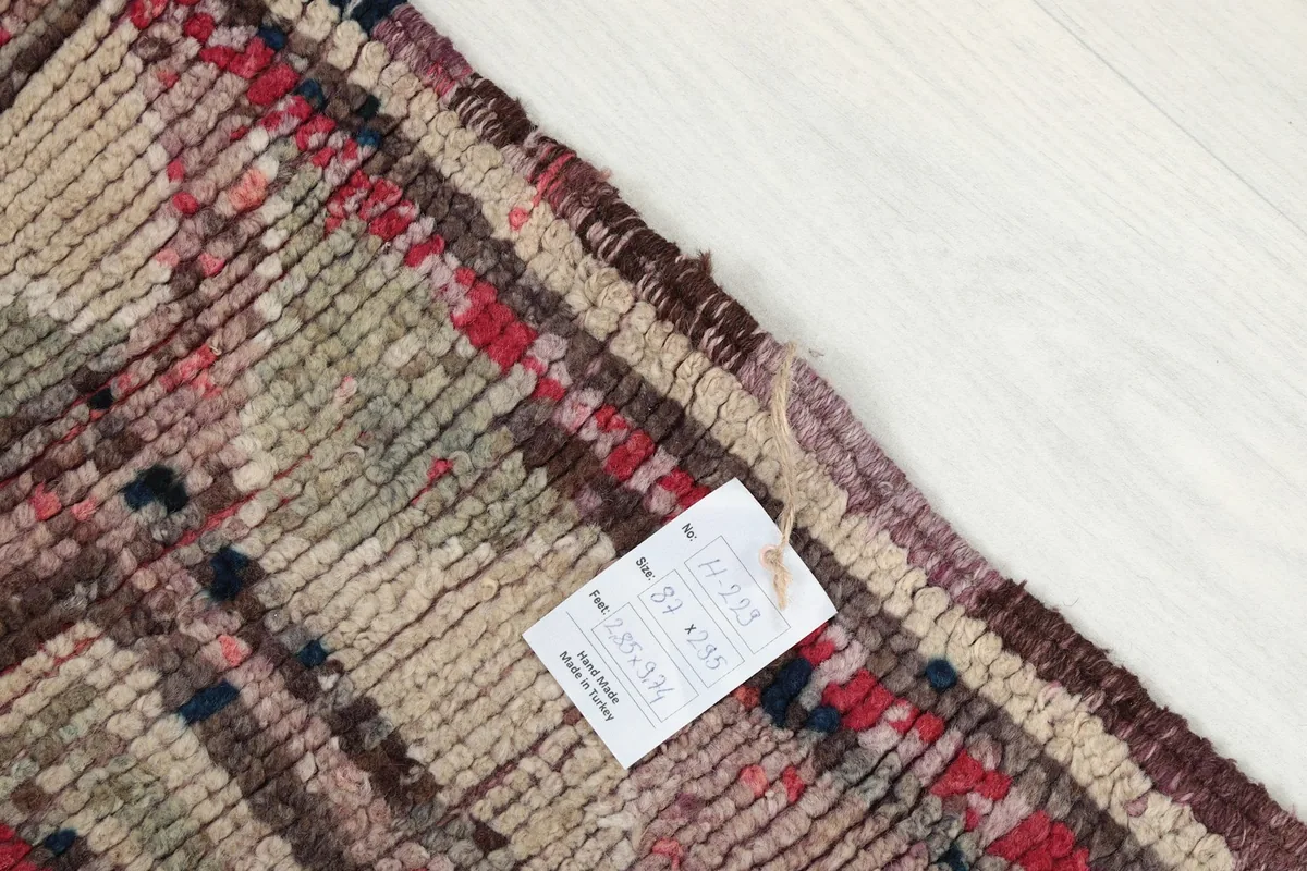 Close-up of the rug's corner with a product tag, showing the hand-knotted wool texture