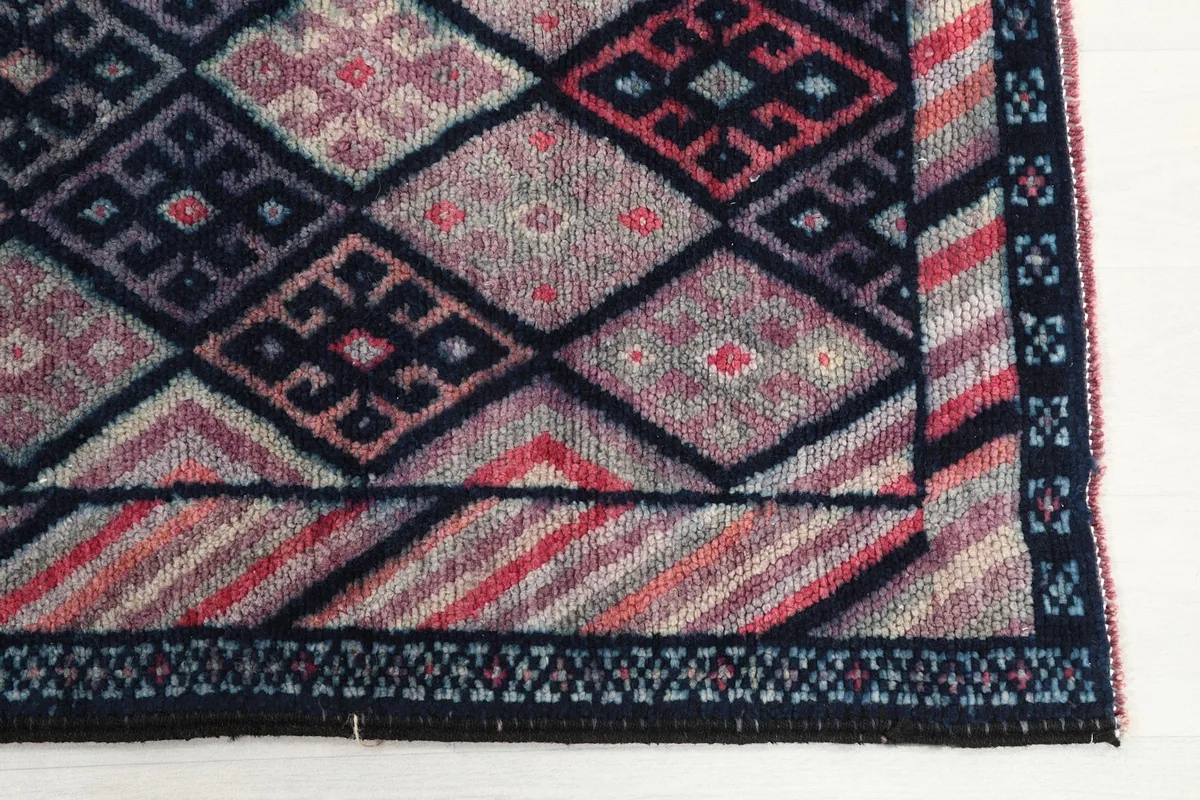 Detailed view of the complex geometric motifs and border design in navy, rose, and cream