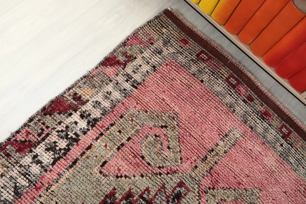 Angled corner view of the rug, detailing the border and field patterns near furniture.