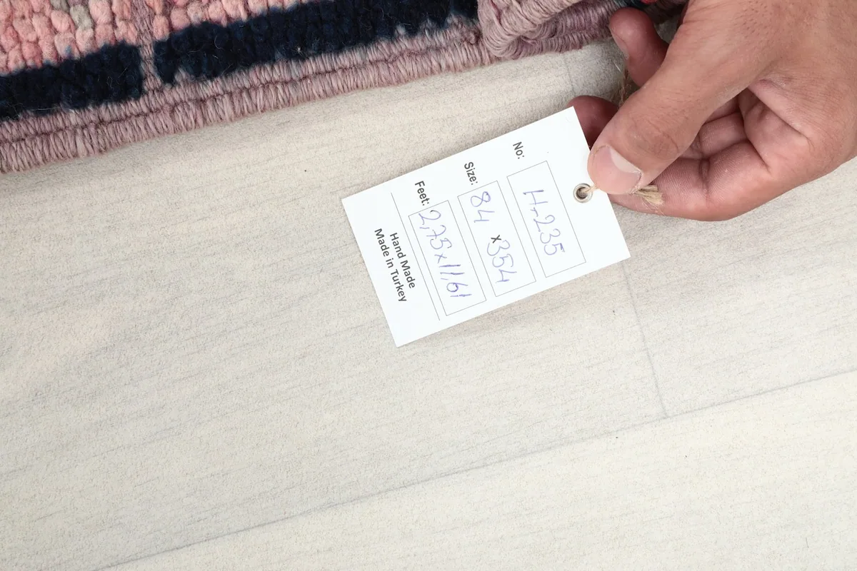 Hand holding the product tag, displaying the rug's size and item number