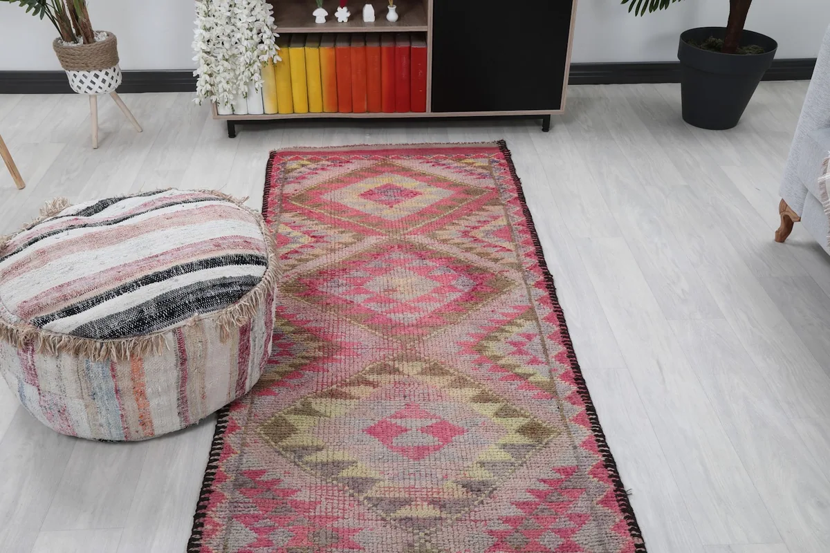 Room view from another angle, showing the runner rug's length and placement next to a pouf