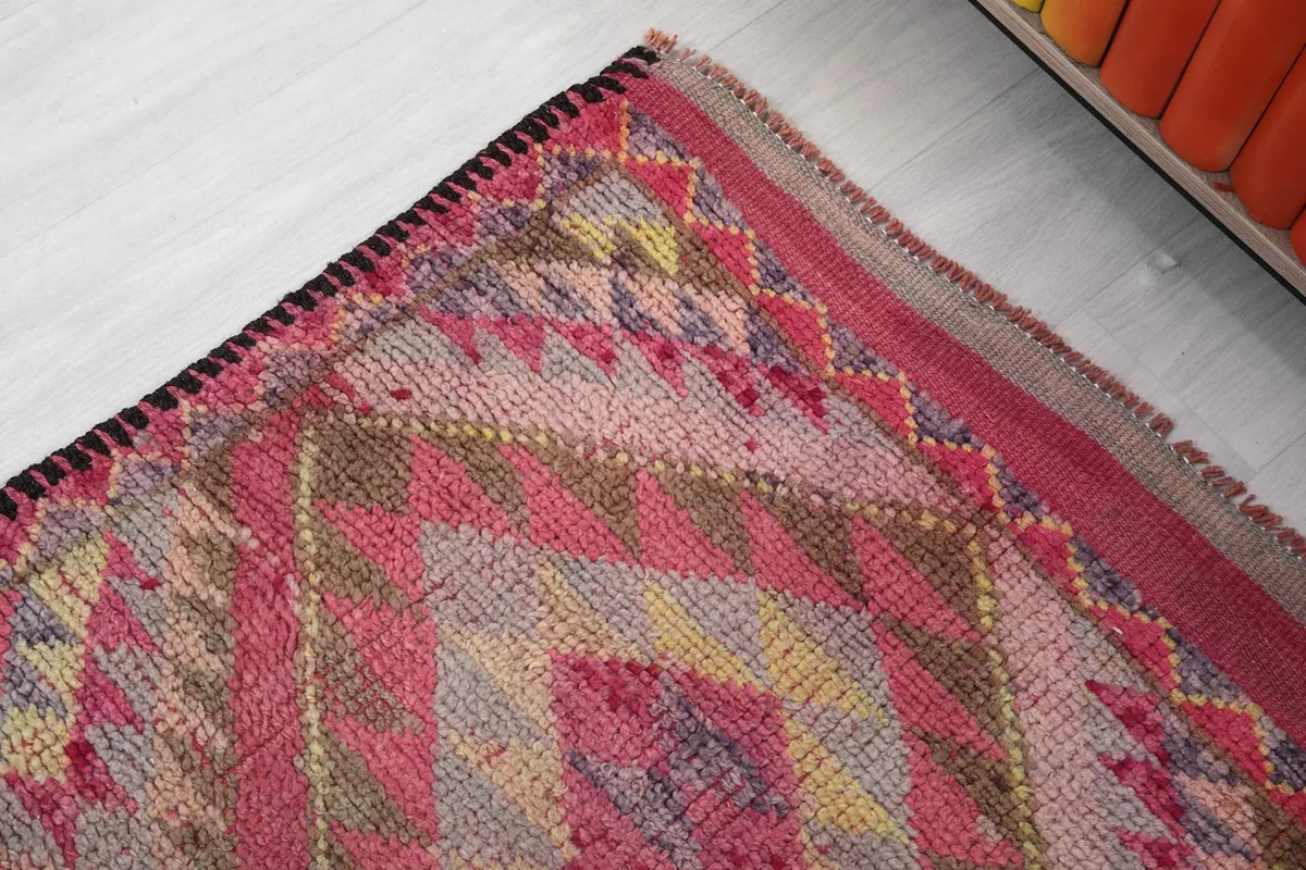 Detail of the rug's edge, showing the tightly woven finish and a glimpse of the dark border