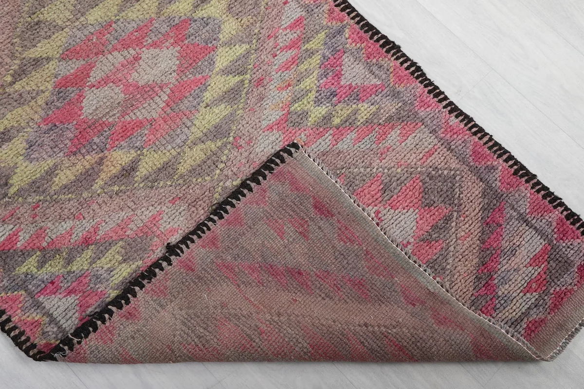 Corner of the rug folded back to reveal the cotton foundation and hand-knotted construction