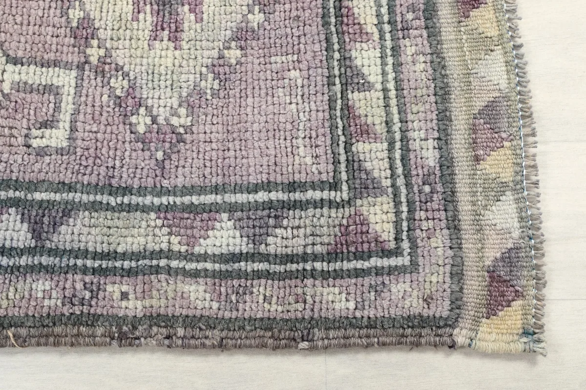 Detailed view of the rug's corner, highlighting the gray and ivory border patterns and rose field