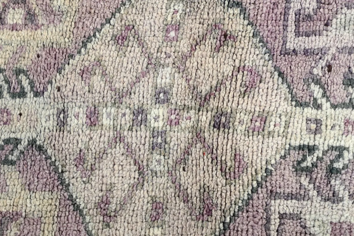 Texture close-up of the hand-knotted wool pile, showing faded rose and ivory colors in a motif