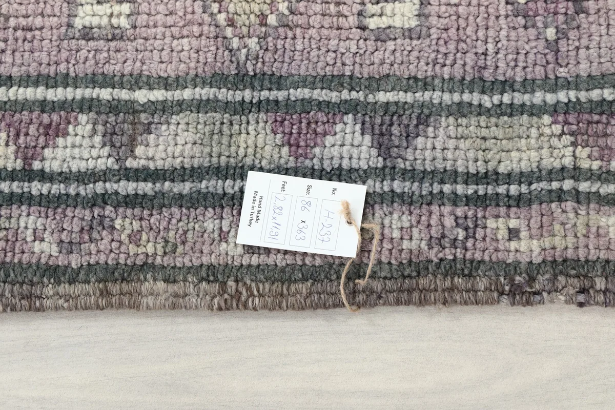 Close-up of the rug's edge with a product tag, showing the wool pile and border details