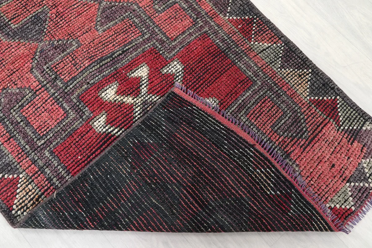 Corner of the rug folded to show the hand-knotted cotton foundation and wool pile