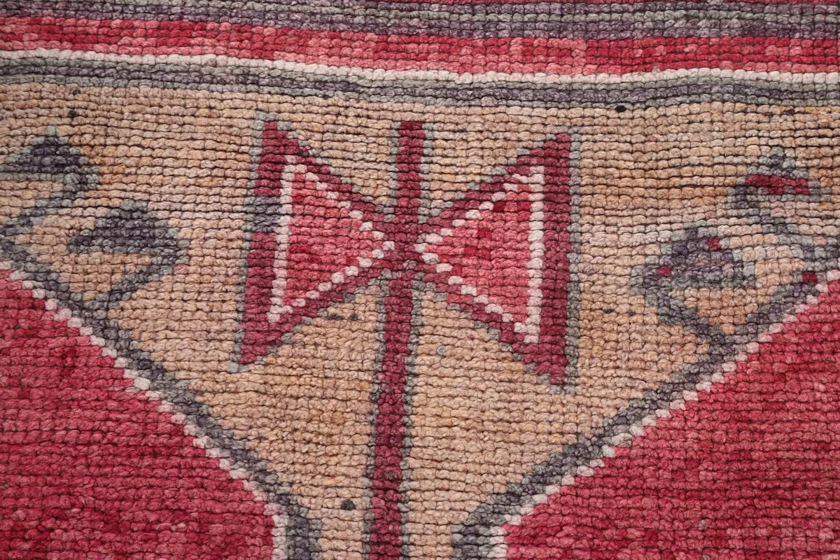 Extreme close-up showing the hand-knotted wool pile and texture of the rug's central motif