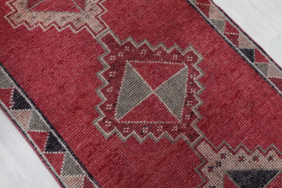 Close-up of a central gray and red diamond motif within the vintage runner's pattern