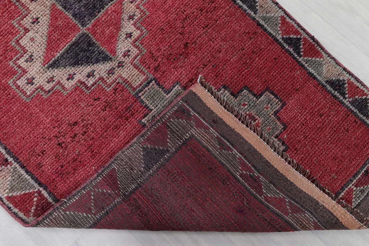 Corner of the runner rug folded to reveal the hand-knotted cotton foundation and reverse side