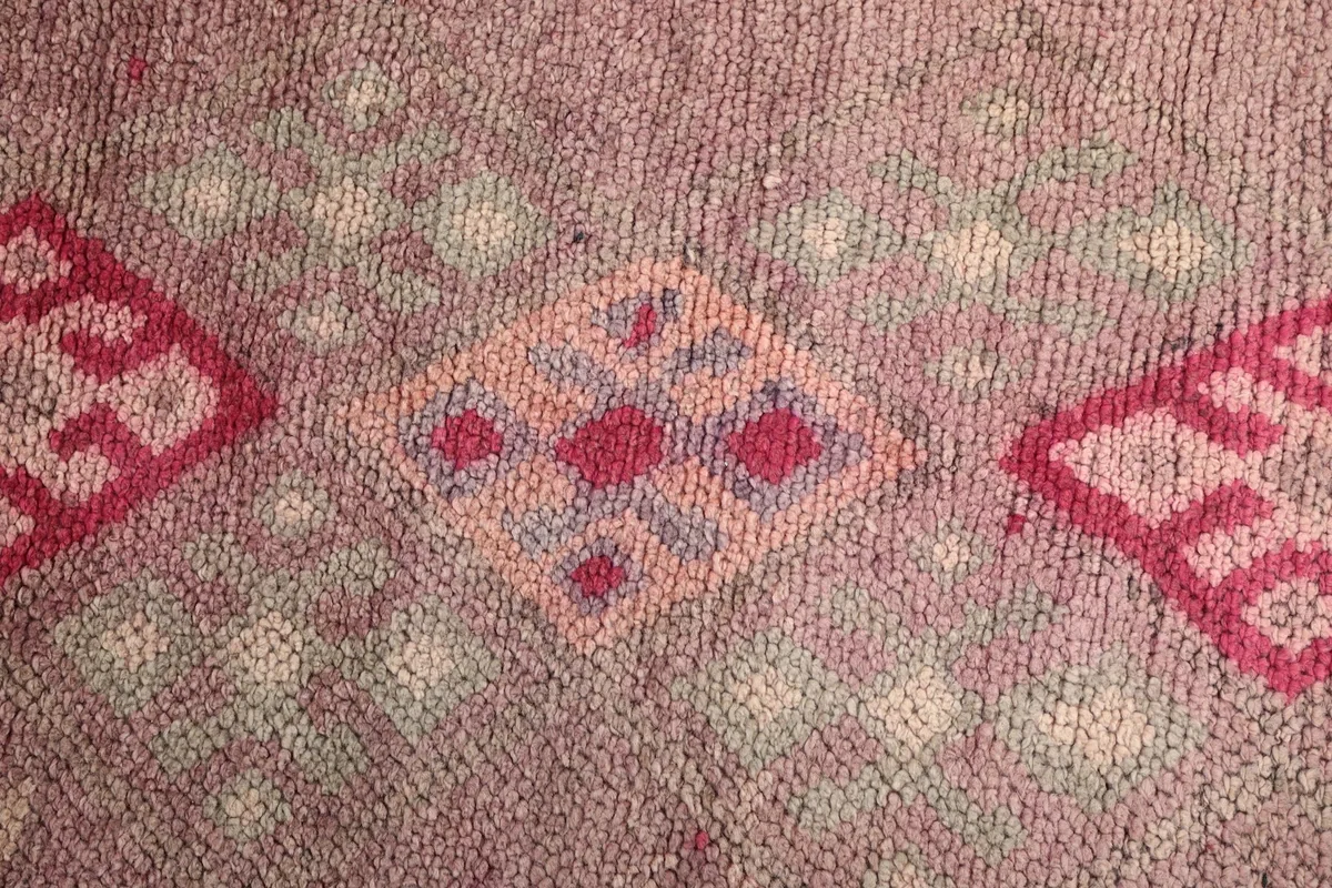 Macro detail of the faded rose and gray wool pile with small geometric designs