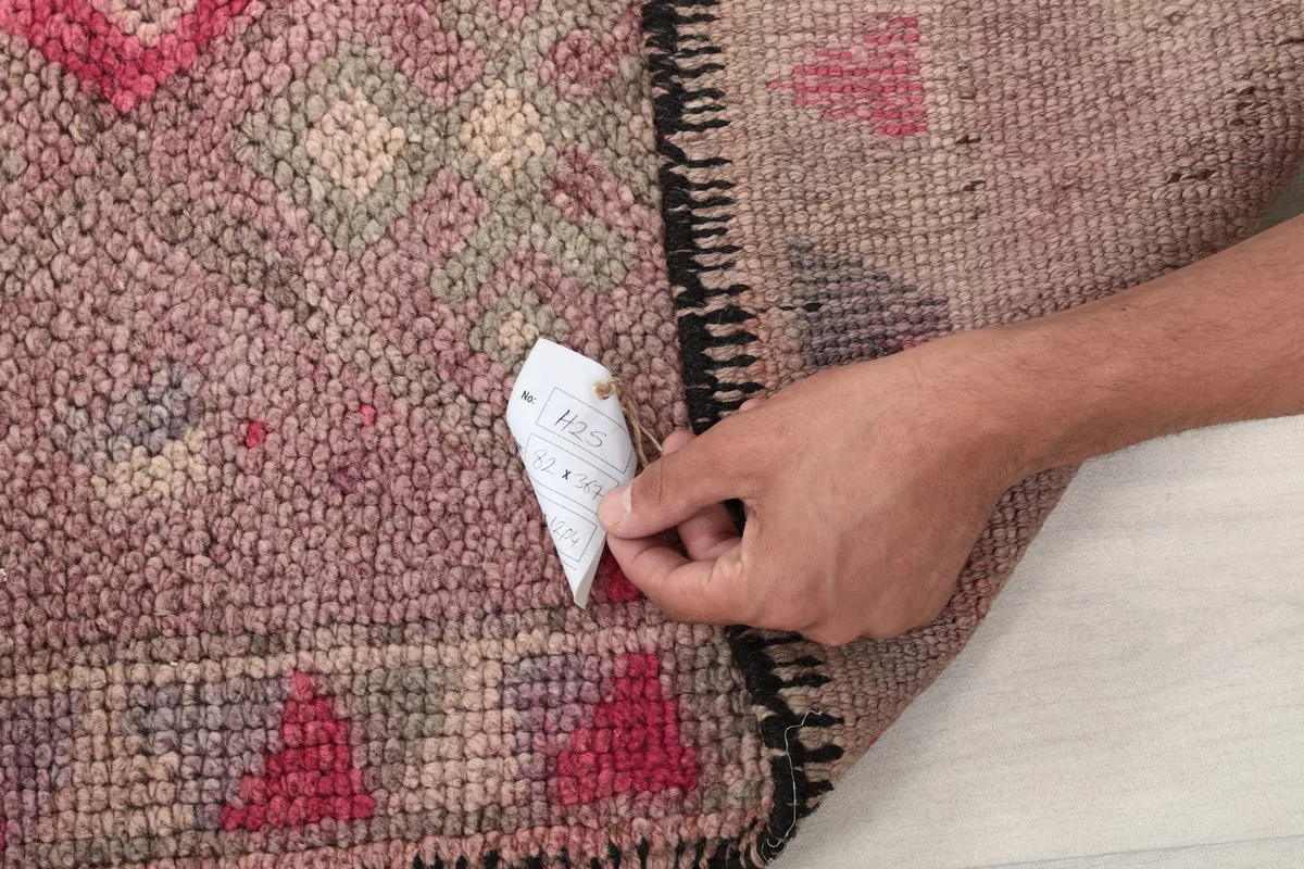 Hand pointing to the low pile of the vintage wool runner, illustrating its texture