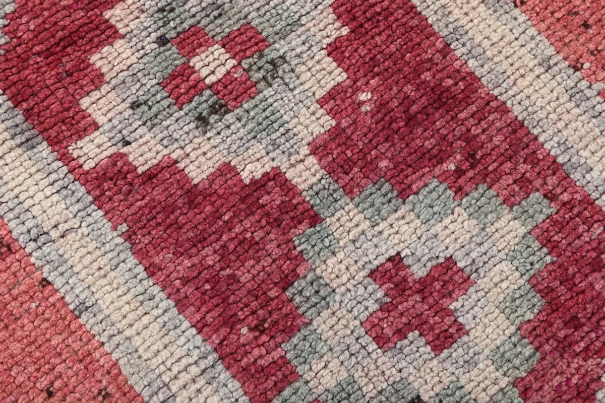 Detailed texture and pattern of the hand-knotted wool pile in rose and gray