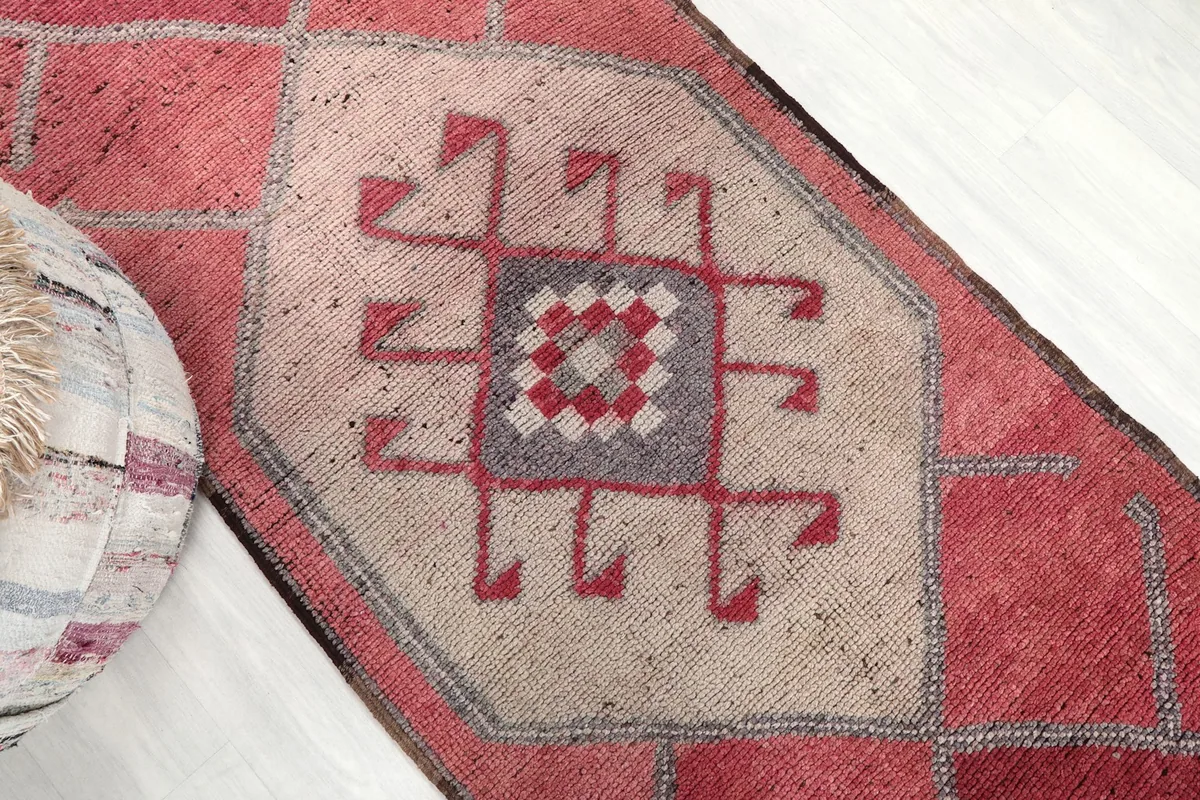 Detailed view of the central beige and rose geometric pattern on the runner rug