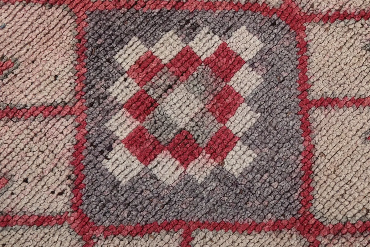 Close-up of the hand-knotted wool pile and intricate pattern details in rose, beige, gray