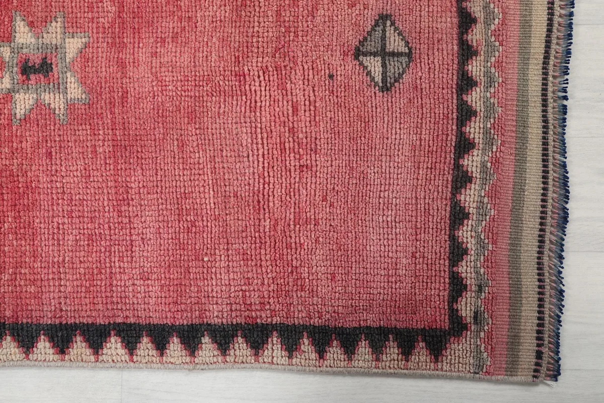 Detailed view of the rose field and charcoal-beige border, showing the texture and low pile of the rug.